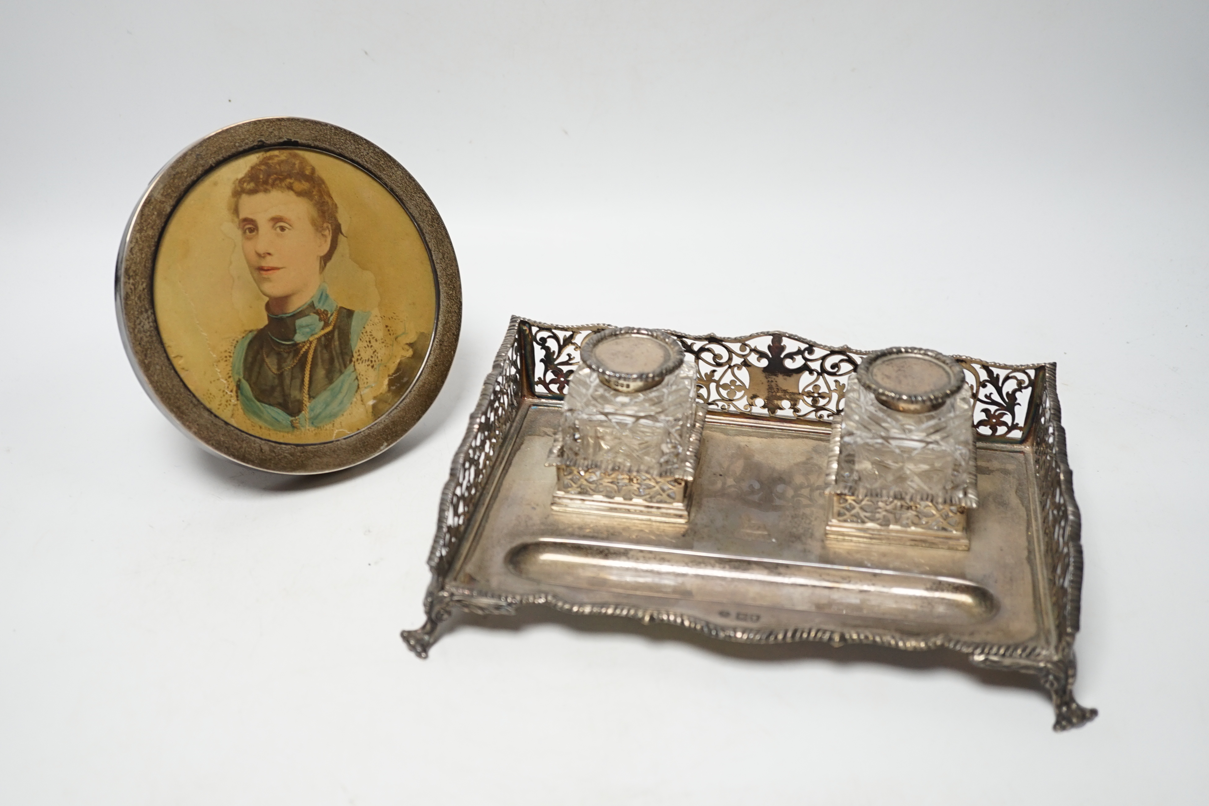 An Edwardian silver rectangular inkstand with pierced three quarter gallery and two mounted cut glass wells, William Hutton & Sons Ltd, London, 1905, 22.3cm and a George V silver mounted circular photograph frame.